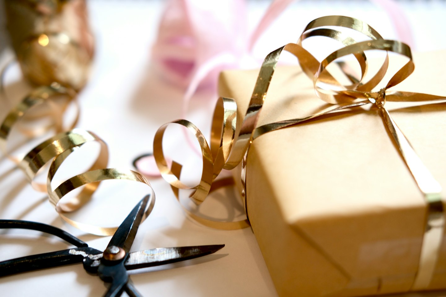 A partially wrapped gift sits with scissors and gold ribbon.