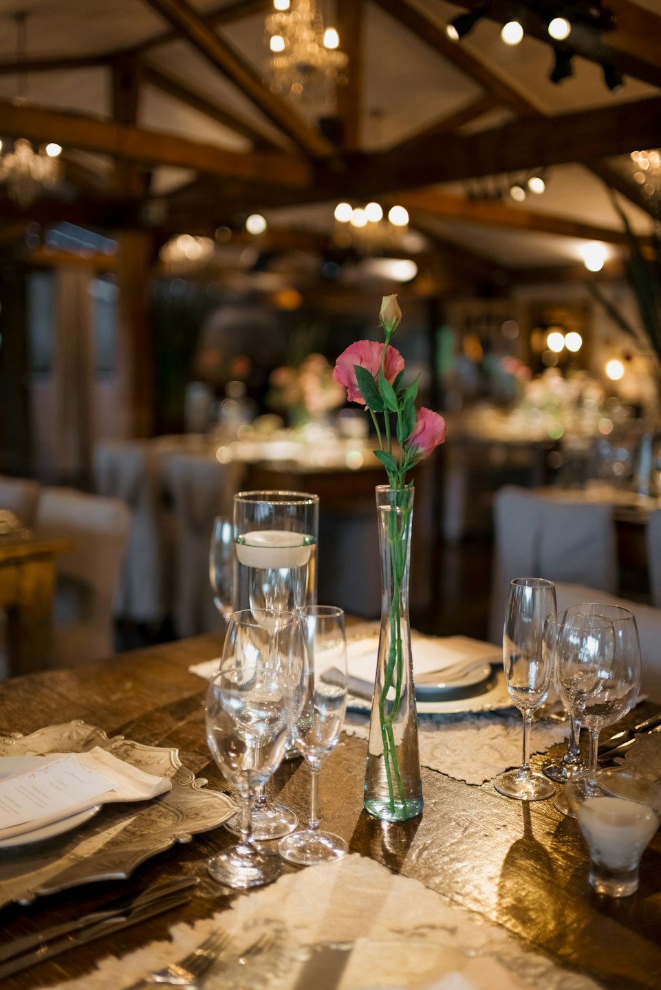 Elegant table setting with crystal glassware and pink flowers.