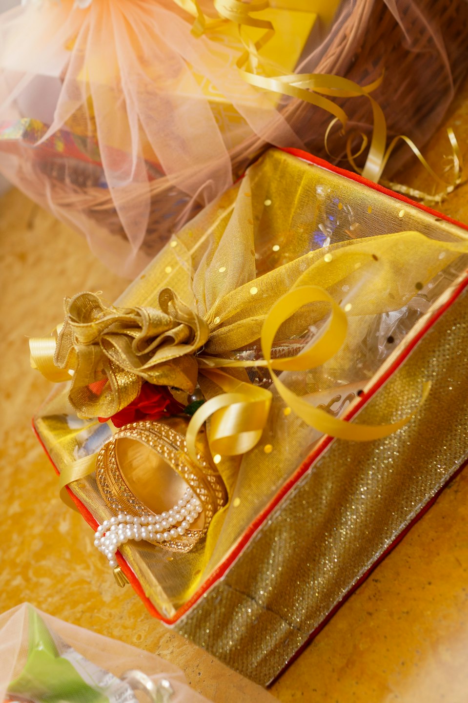 Luxurious gift box containing golden bangles and white pearls.