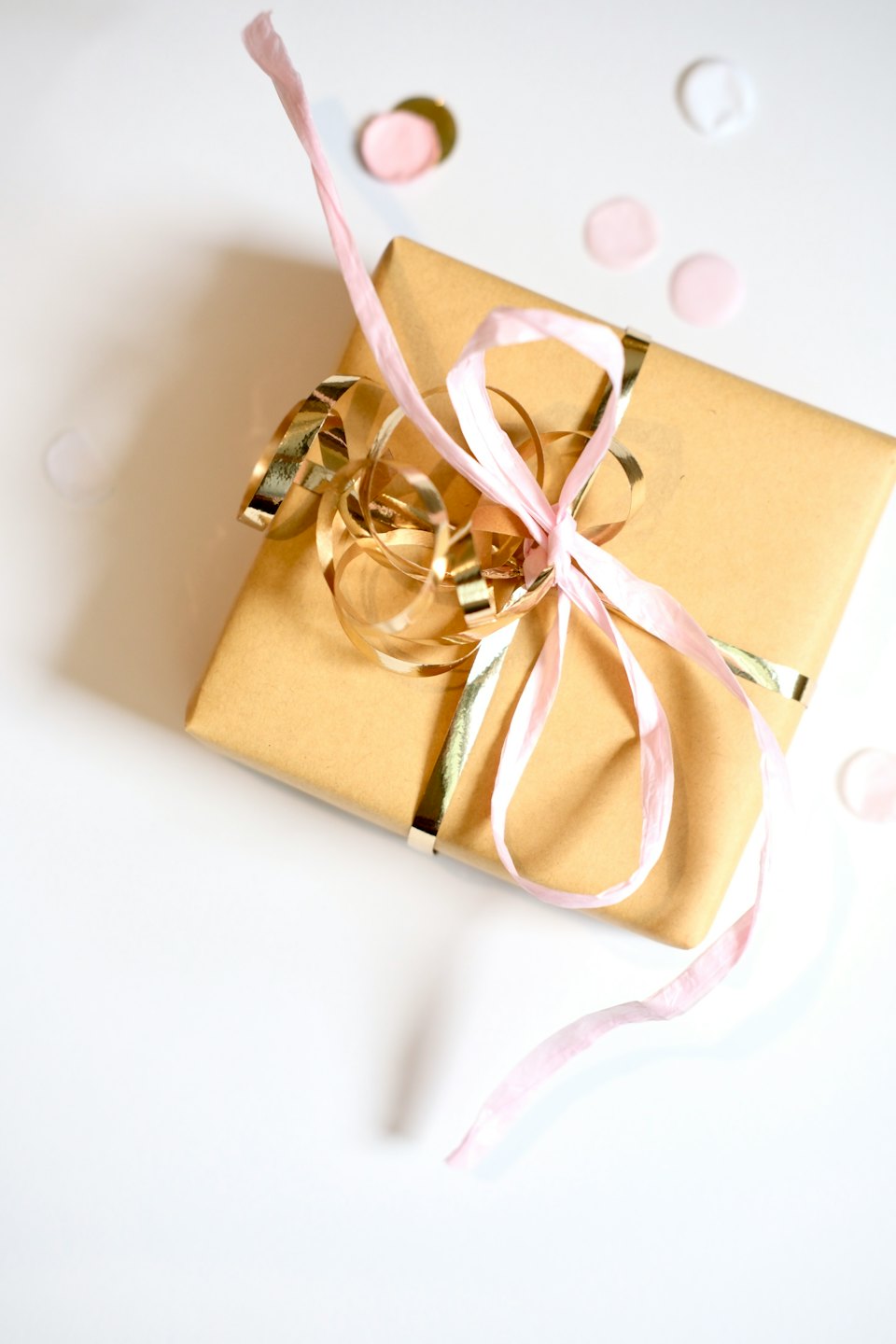 Brown gift box decorated with gold and pink ribbons.