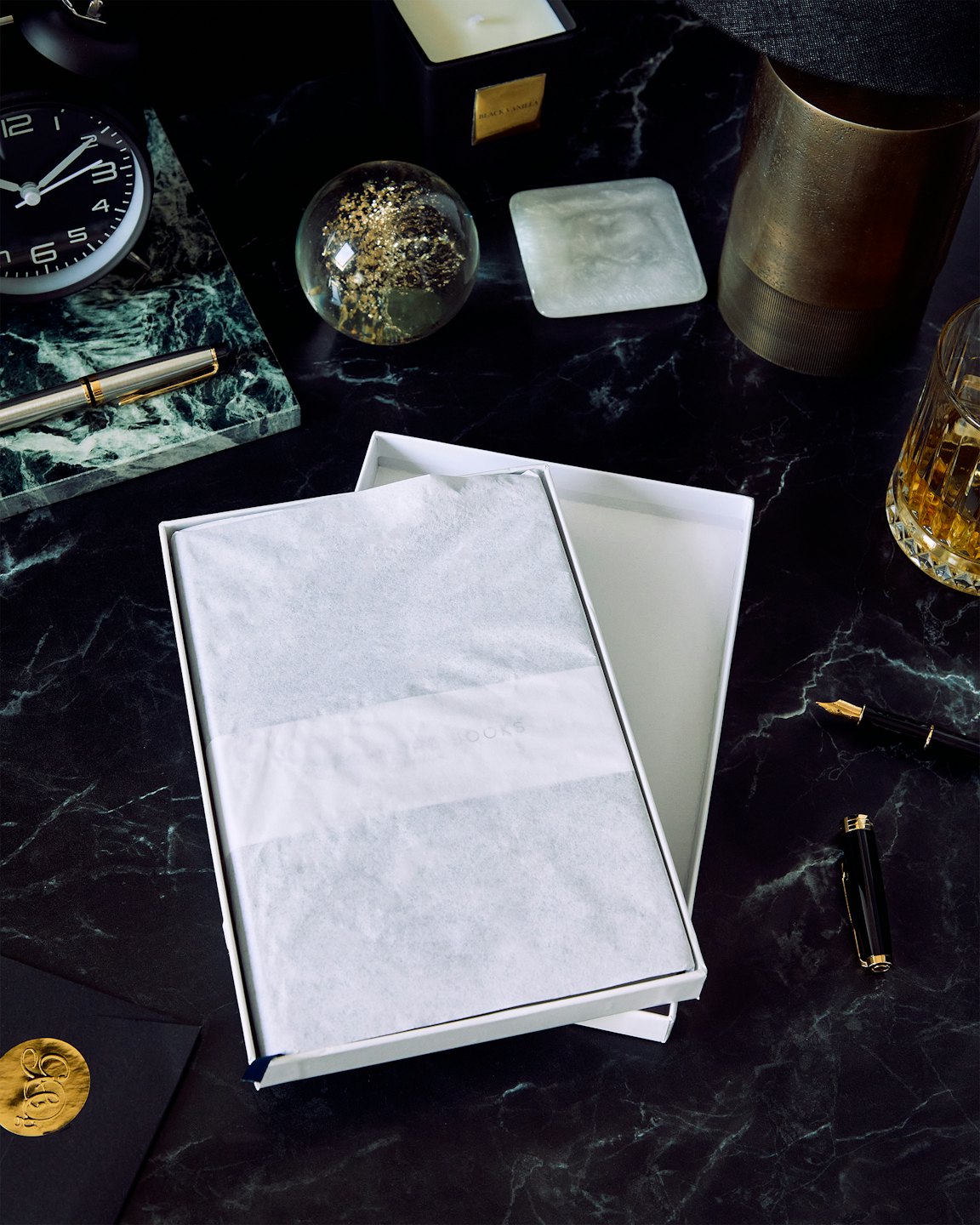 An open gift box rests among luxury desk accessories.